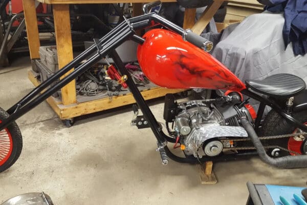 A red motorcycle is sitting in the middle of a garage.