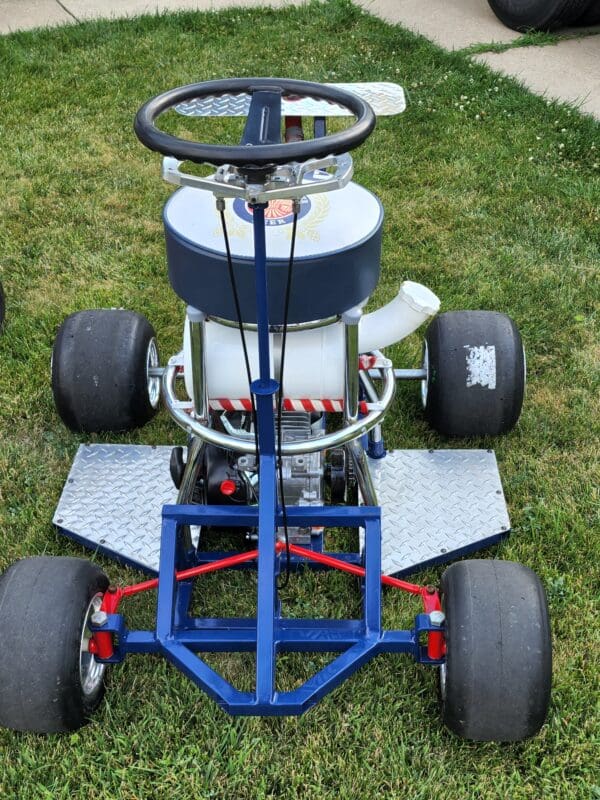 A blue and white kart sitting on top of grass.