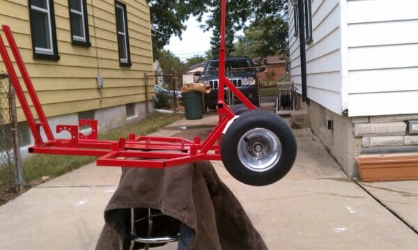 A red trailer with wheels on the ground.