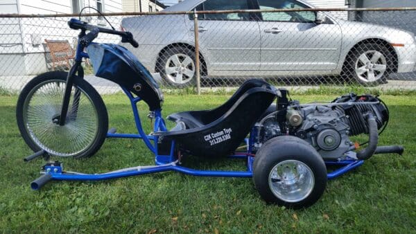 A blue and black trike is parked in the grass.