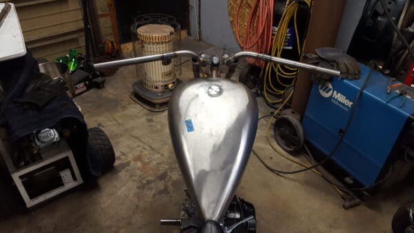 A motorcycle is parked in the garage with its handlebars.