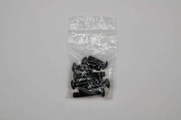 A bag of black screws sitting on top of a table.